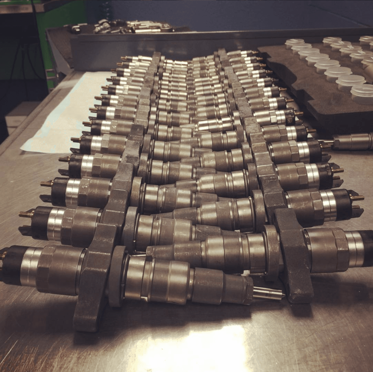 Row of remanufactured common rail diesel injectors on a workbench